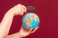 Image of a hand holding a magnifying glass over an world globe Royalty Free Stock Photo