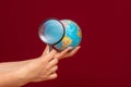 Image of a hand holding a magnifying glass over an world globe Royalty Free Stock Photo