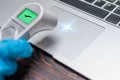 Image of a hand in a medical glove measuring the temperature of a laptop. Antivirus systems concept. Protecting your computer from