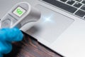 Image of a hand in a medical glove measuring the temperature of a laptop. Antivirus systems concept. Protecting your computer from
