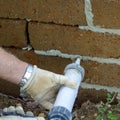 Image of the hands of a mason while filling joints in a tuff brick wall. Royalty Free Stock Photo