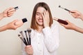 Image of the hands of several beauticians holding their respective equipment giving makeover to beautiful smiling woman with