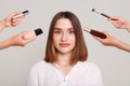 Image of the hands of several beauticians and stylists holding their respective equipment giving a glamour makeover to a beautiful