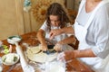 Cropped image of the hands of a woman and a child kneading dough. Ingredients for baking arranged on a wooden table. Royalty Free Stock Photo
