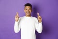 Image of handsome african-american young guy in white sweatshirt, looking hopeful and smiling with crossed fingers