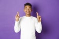 Image of handsome african-american young guy in white sweatshirt, looking hopeful and smiling with crossed fingers