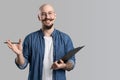 Image of handsome balded with musctache and beard happy man wearing casual clothes holding clipboard and writing while