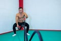 Image of a handsome muscular young man using battle ropes for exercise in a gym. He focuses on performing the exercise. Royalty Free Stock Photo