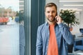 Image of handsome serious young man talking cellphone while working at office. Royalty Free Stock Photo