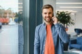 Image of handsome serious young man talking cellphone while working at office. Royalty Free Stock Photo