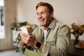 Image of handsome young man in cafe, looking at his mobile phone, using smartphone app, drinking coffee Royalty Free Stock Photo