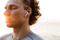 Handsome young sports man standing on the beach listening music with earphones. Royalty Free Stock Photo