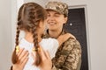 Image of happy attractive military woman wearing camouflage uniform and cap posing with her daughter, people hugging each other, Royalty Free Stock Photo