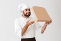 Image of happy baker man in cook uniform smelling while holding pizza box Royalty Free Stock Photo