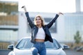 Image of happy blonde with keys sitting on hood of black car