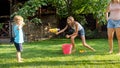 Image of happy cheerful family playing in the backyard garden. People splashing water with water guns and garden hose. Royalty Free Stock Photo