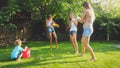 Image of happy cheerful family playing in the backyard garden. People splashing water with water guns and garden hose. Royalty Free Stock Photo