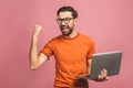 Image of happy excited young man posing isolated over pink background wall using laptop computer make winner gesture Royalty Free Stock Photo