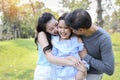 Image of happy family, daughter putting her hands on parents cheek with smiling while father and mother kissing during summer time Royalty Free Stock Photo