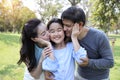 Image of happy family, daughter putting her hands on parents cheek with smiling while father and mother kissing during summer time Royalty Free Stock Photo