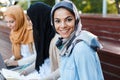 Image of happy friends muslim sisters students women sitting outdoors.