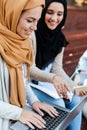 Image of happy friends muslim sisters women sitting outdoors