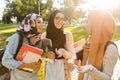 Image of happy friends muslim sisters women walking outdoors holding books Royalty Free Stock Photo