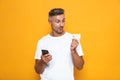 Image of happy guy 30s in white t-shirt holding mobile phone and credit card Royalty Free Stock Photo