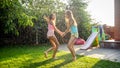 Photo of happy laughing children in wet clothes jumping and dancing under warm rain at garden. Family playing and having Royalty Free Stock Photo