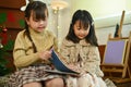 Image of happy little siblings reading a storybook together in cozy living room decorated for Christmas