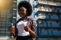 Image of a happy optimistic emotional young american african woman posing over city background