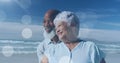 Image of happy senior african american couple embracing at beach over light spots Royalty Free Stock Photo