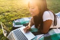 Smiling young asian girl outdoors in park using laptop computer. Royalty Free Stock Photo