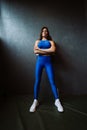 Image of happy sports young girl standing and posing over black wall. Looking at camera. Female resting after fitness. Royalty Free Stock Photo