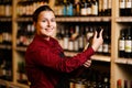 Image of happy woman with bottle in her hands in wine shop