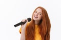 Image of happy woman with curly hair singing while holding microphone isolated over white background Royalty Free Stock Photo