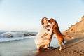 Image of happy woman 20s hugging her dog, while walking along the beach Royalty Free Stock Photo