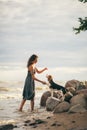 Image of happy woman 20s hugging her dog while walking along the beach Royalty Free Stock Photo