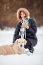 Image of happy woman in scarf sitting next to labrador at winter