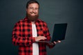 Image of happy young bearded man standing over grey wall background isolated. Looking camera using laptop Royalty Free Stock Photo