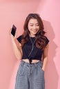 Image of a happy young beautiful woman posing isolated over pink wall background listening music with earphones using mobile phone Royalty Free Stock Photo