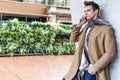 Image of happy young man standing on the street while talking by his phone Royalty Free Stock Photo