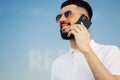 Image of a happy young man walking down the street and looking to the side, talking on a mobile phone Royalty Free Stock Photo