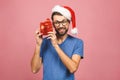 Image of happy young man wearing christmas santa hat standing isolated over pink wall holding gift box Royalty Free Stock Photo
