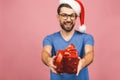 Image of happy young man wearing christmas santa hat standing isolated over pink wall holding gift box Royalty Free Stock Photo