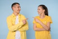 Image of happy young people man and woman in yellow shirts laughing and pointing fingers at each other isolated over Royalty Free Stock Photo