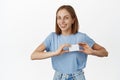 Image of happy young woman showing discount, credit card near heart, likes bank new offer, cashback or deposit proposal