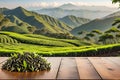 Wooden table top surface in foreground, sharpness out of focus: tea plantation undulating, mountain backdrop