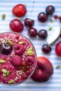 Image of homemade antioxidant berry smoothie with seeds, coconut, cherries and rasberry. Delicious dessert on violet