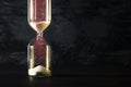 Image of hourglass as time passing concept over black background for business deadline. Glitter overlay. Royalty Free Stock Photo